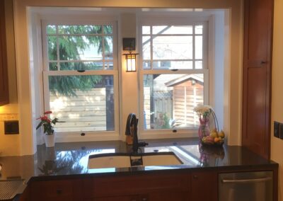 A well-lit kitchen featuring wooden cabinets, stainless steel appliances, and a window above the sink overlooking the outdoor area.