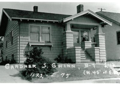 Black and white photograph of a modest single-story house with handwritten annotations at the bottom.