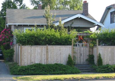 Suburban house with a wooden fence and landscaped front yard.